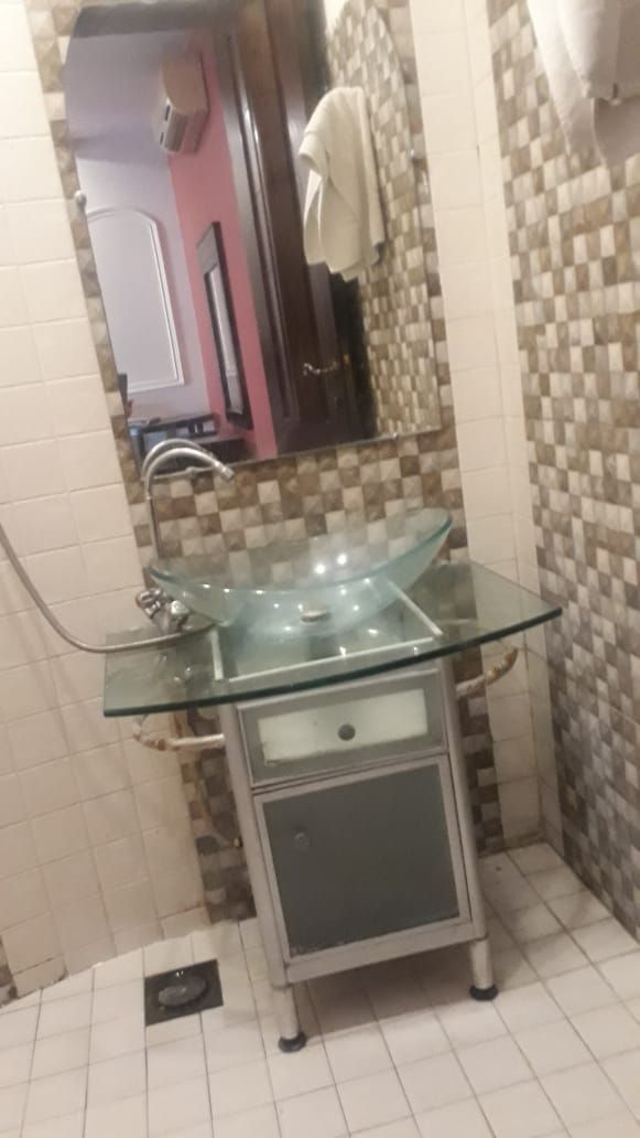 A bathroom with a glass sink, a mirror, and a tiled wall.