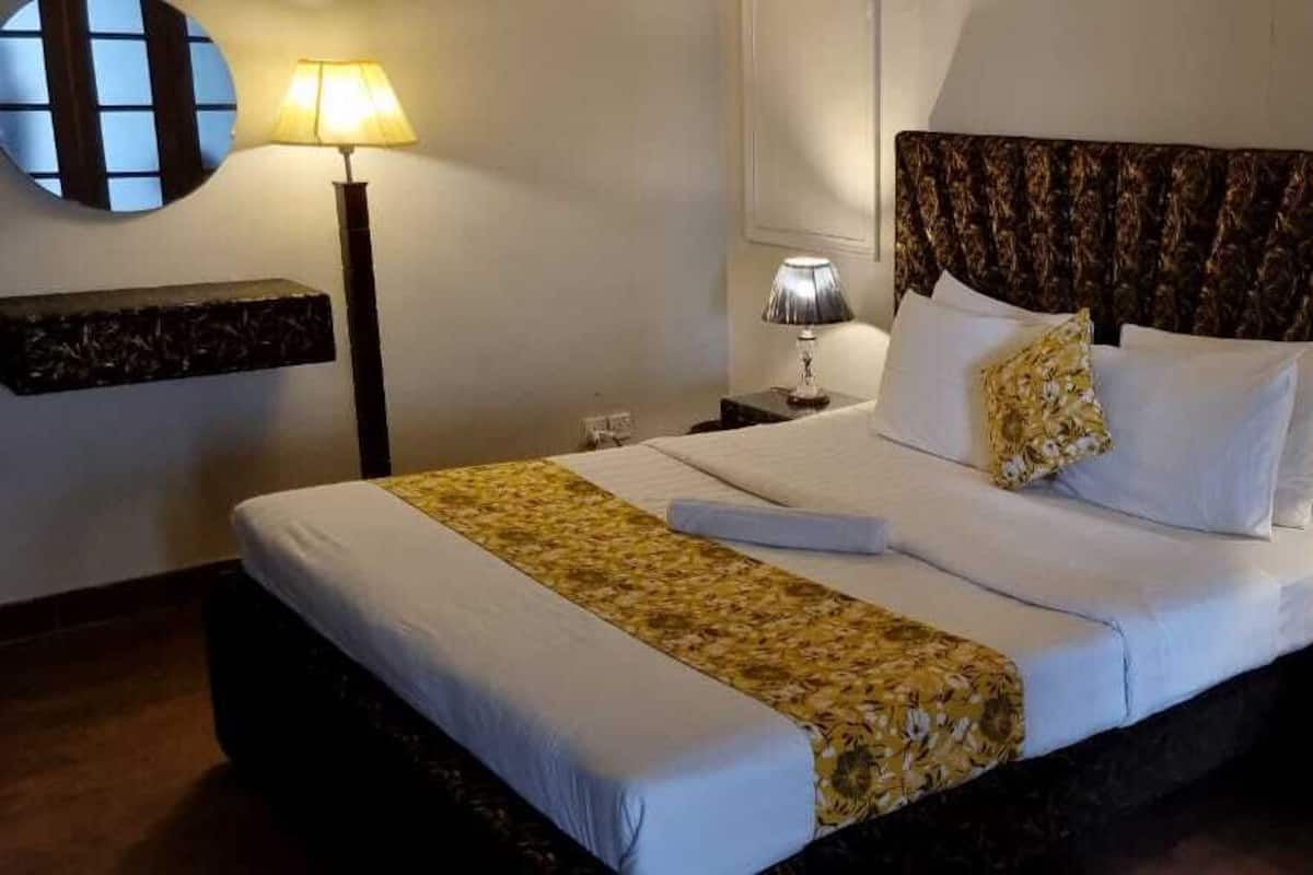 A neatly made bed with white linens and a floral throw blanket, two bedside lamps, and a marble-patterned headboard.