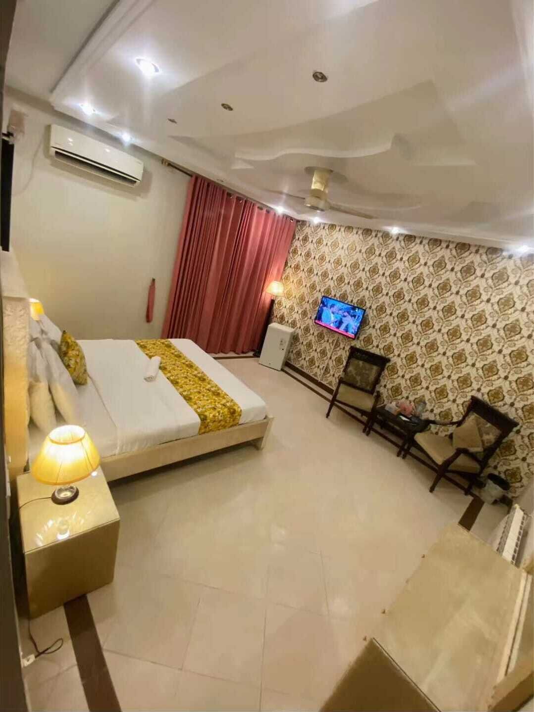 A hotel room with a bed, a TV, a desk, and a chair.