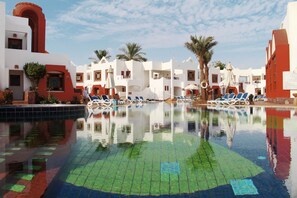A swimming pool with lounge chairs and palm trees, surrounded by white and red buildings. - Sharm Inn Amarein - Boutique Hotel (Sharm El Sheikh)