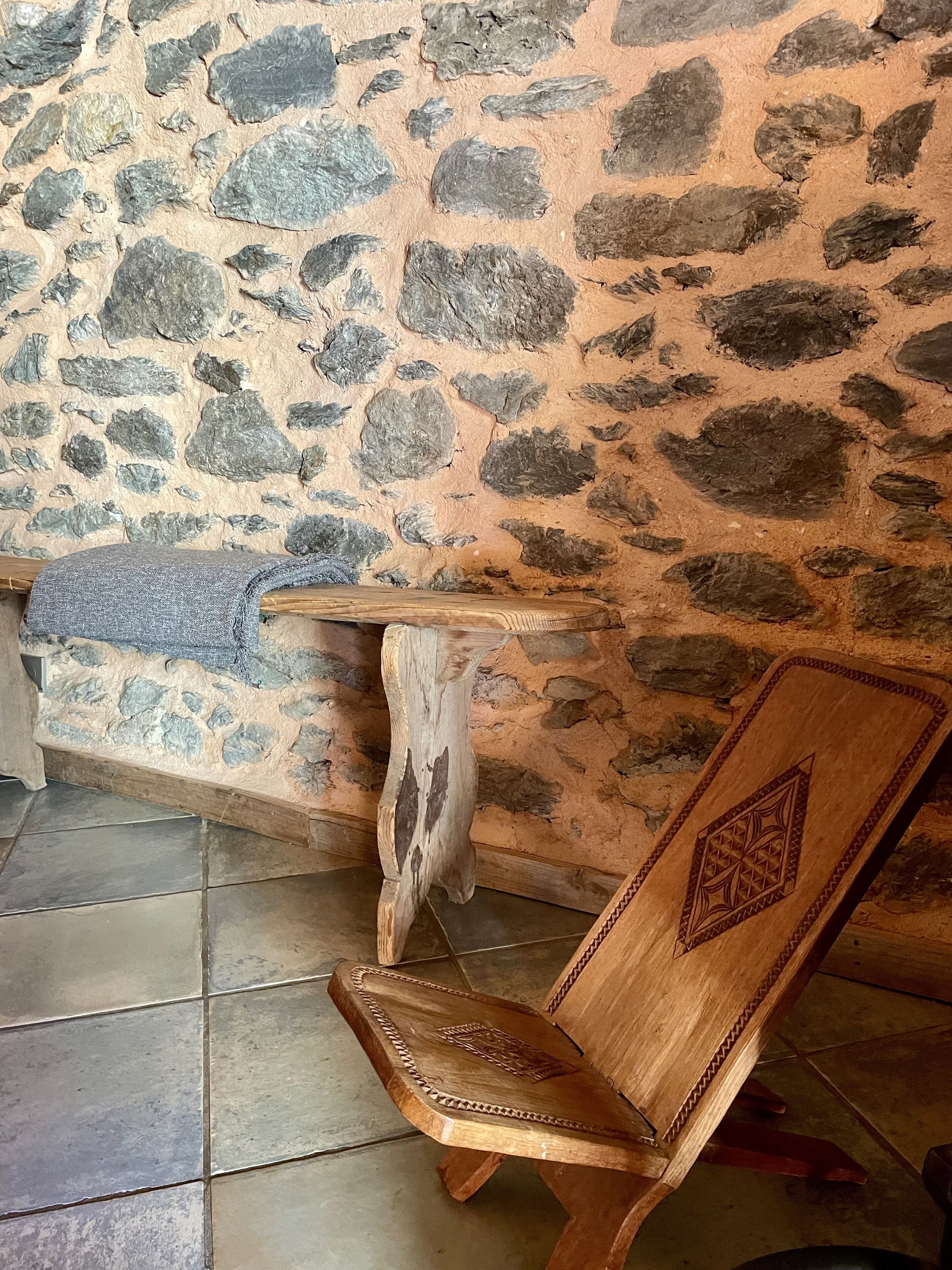 Un mur de pierre avec un banc en bois et une petite table.