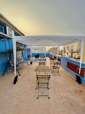 Relax on the rooftop terrace with comfortable seating under a shaded canopy.
