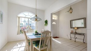 A dining area with a table, chairs, and a hanging light fixture. - Private Pool Villa Near Disney with Golf, Patio & Resort Amenities (Davenport)