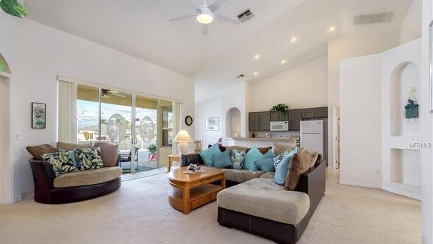 A spacious living room with a large sectional sofa, a coffee table, and a dining area with a lamp. - Private Pool Villa Near Disney with Golf, Patio & Resort Amenities (Davenport)
