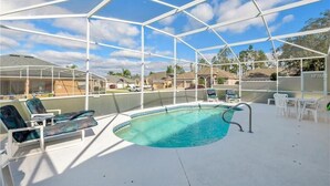 A covered swimming pool with lounge chairs and a pool table, surrounded by a white fence. - Private Pool Villa Near Disney with Golf, Patio & Resort Amenities (Davenport)