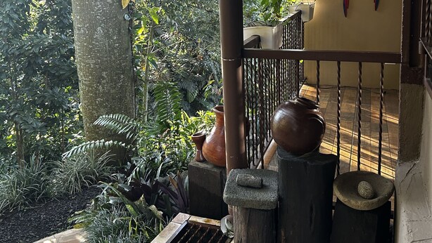 A covered outdoor area with a metal railing, a stone bench, and a decorative wall with bird figures.