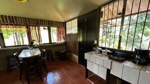 A kitchen with a dining table, chairs, a stove, and a window with curtains.