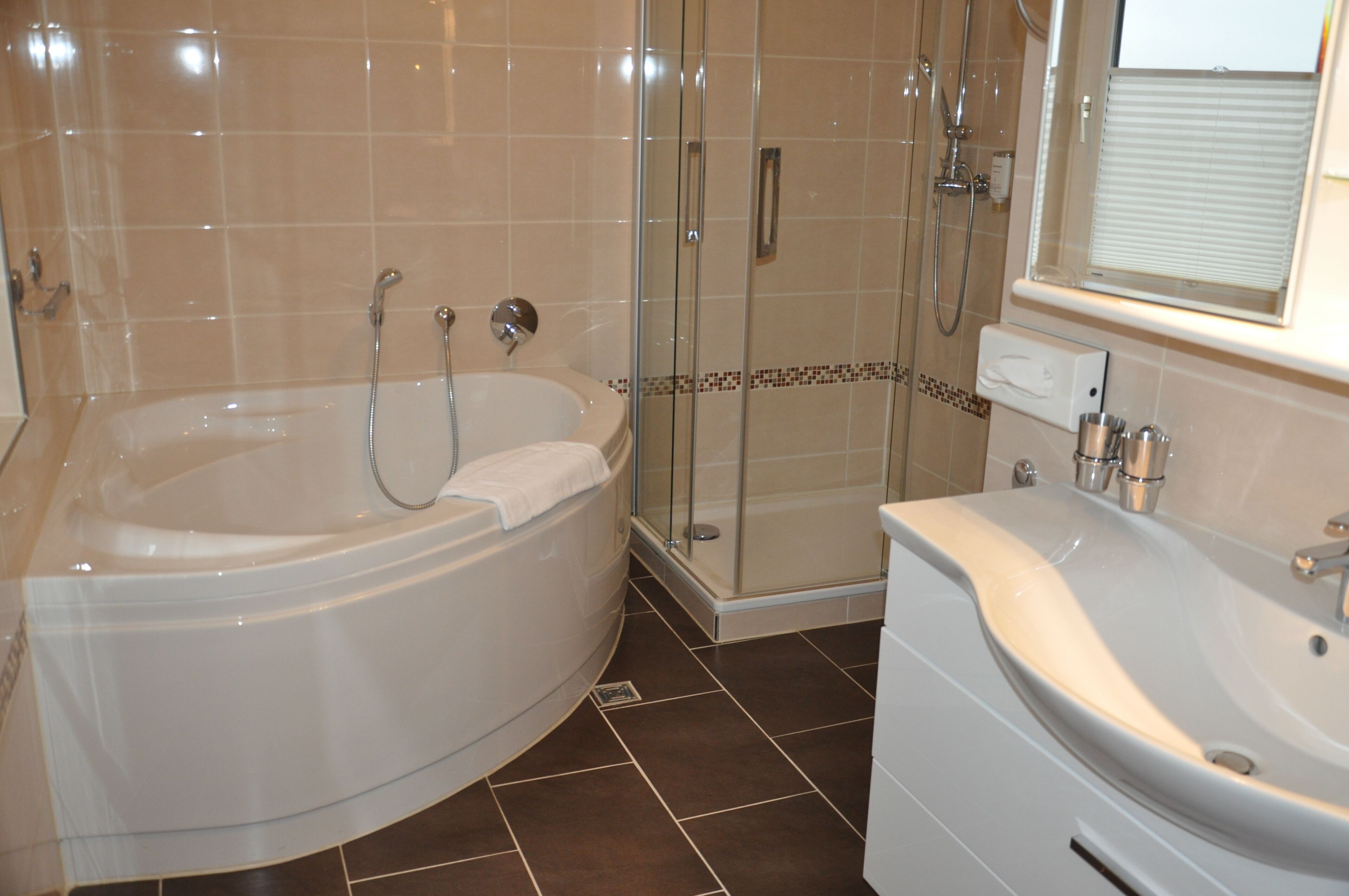 Un baño moderno con una bañera independiente, ducha con mampara de vidrio y tocador con lavabo y espejo.
