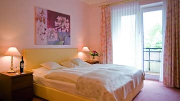 Una cama bien hecha con una colcha estampada con flores, dos lámparas de noche, una mesita de noche y un cuadro de flores en la pared.