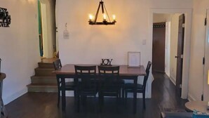 Ein Essbereich mit Tisch und Stühlen, einer Kandelaberleuchte und einer Treppe zu einem weiteren Raum.