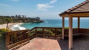 A wooden gazebo with a brick floor overlooking a beach with waves crashing onto the shore. - Ocean View, Gym, Sauna, Garden, and Private Beach! (Laguna Beach)