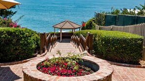 A gazebo with a view of the ocean, surrounded by a brick pathway and a flower bed. - Ocean View, Gym, Sauna, Garden, and Private Beach! (Laguna Beach)