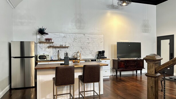 A modern kitchen with a marble backsplash, stainless steel appliances, and a wooden bar area with bar stools. - Vaudeville Suite, Romantic King Stay Just 4 Min from Hermann Wineries (Hermann)