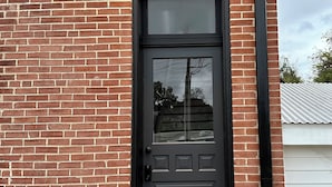 A brick building with a black door, a small porch, and a doormat with an 'M'. - Vaudeville Suite, Romantic King Stay Just 4 Min from Hermann Wineries (Hermann)