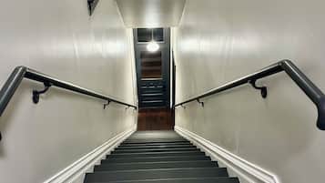 A staircase with dark wooden steps and white walls, leading to a door at the top.