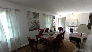 A dining area with a wooden table and chairs, a rug, and a lamp.