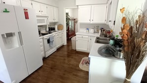A kitchen with white cabinets, a refrigerator, a stove, and a sink.