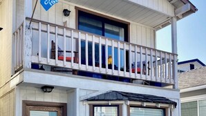 A two-story building with a balcony, a flag, and a sign indicating a vacation rental. - Catalina Is. Home close to Beach (Avalon)