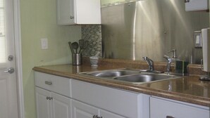 A kitchen with white cabinets, a stainless steel refrigerator, a double sink, and hanging pendant lights. - LOVELY APARTMENT 1 MILE TO BEACH - DEERFIELD BEACH - FREE PARKING (Deerfield Beach)