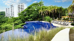 Une piscine d’un complexe hôtelier offrant une vue dégagée sur la végétation environnante et sur un bâtiment situé au loin.