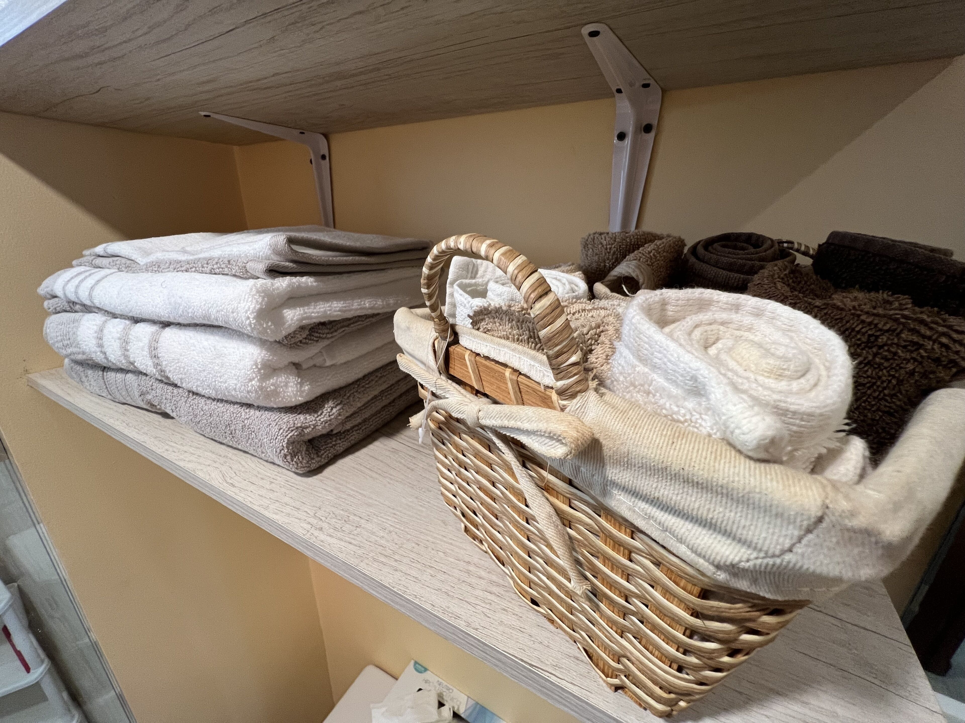 Une étagère avec des serviettes soigneusement pliées et un panier en osier contenant d’autres serviettes pliées.