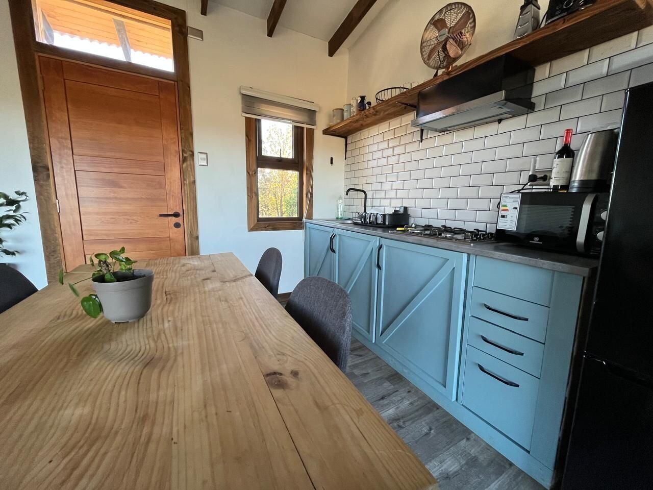 A kitchen with a wooden table, blue cabinets, and a window.