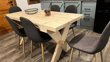 A wooden dining table with four chairs, a black basket, and a glass container with utensils.
