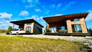 Two modern houses with large windows and a car parked in front. - Cabañas Lawal Pto Varas (Puerto Varas)