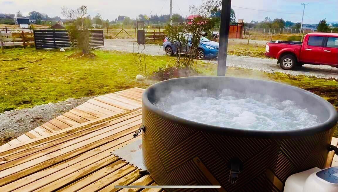 A hot tub on a wooden deck with a view of a rural landscape.