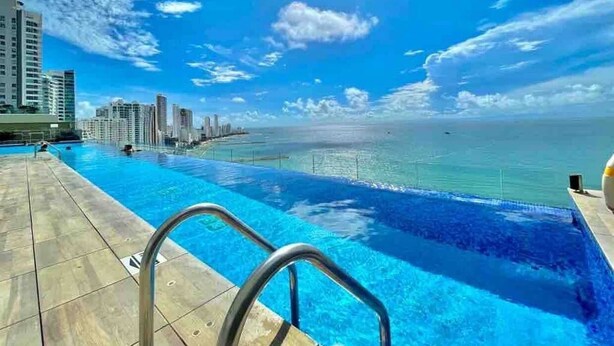 A swimming pool with a view of the ocean and city skyline. - Condominio H2 (Cartagena)