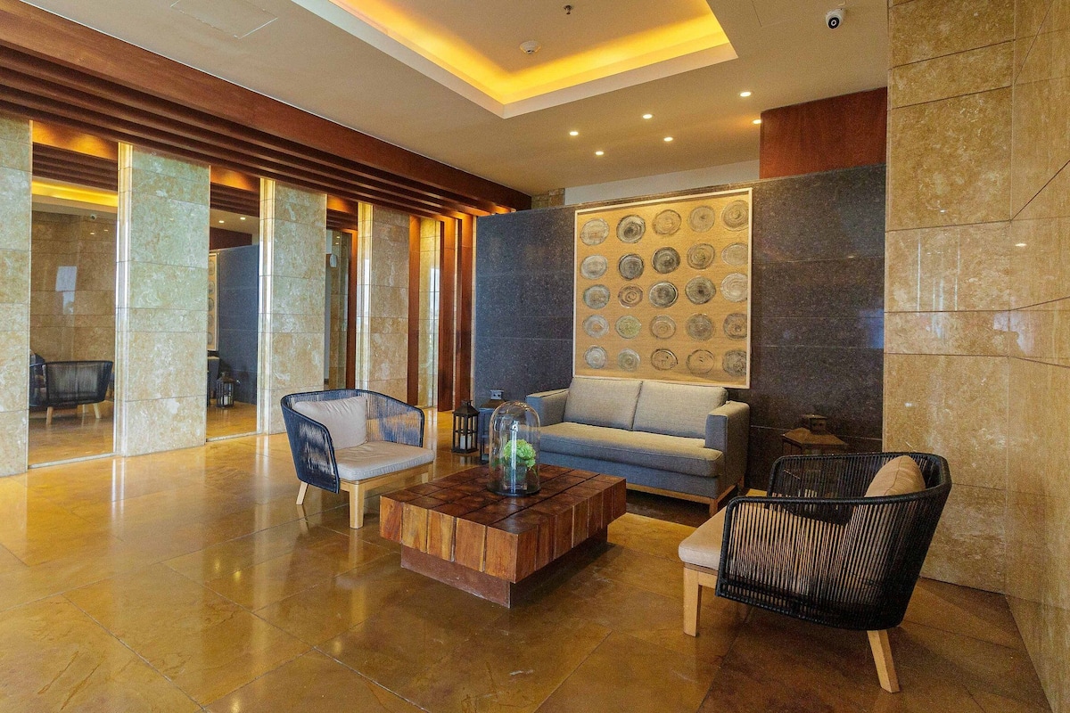 A spacious lobby with a wooden ceiling, a large wall art piece, and a seating area with a sofa and chairs.