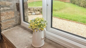 A window with a stone wall and a view of a garden with a wooden fence and gravel path. - The Stable (Narberth)