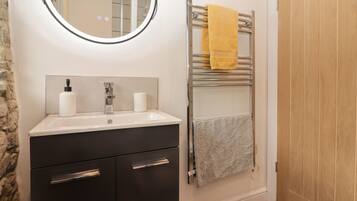 A bathroom with a sink, mirror, towel rack, and wooden door.