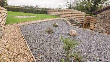 A gravel patio with wooden fences, a small plant, and a stone wall.