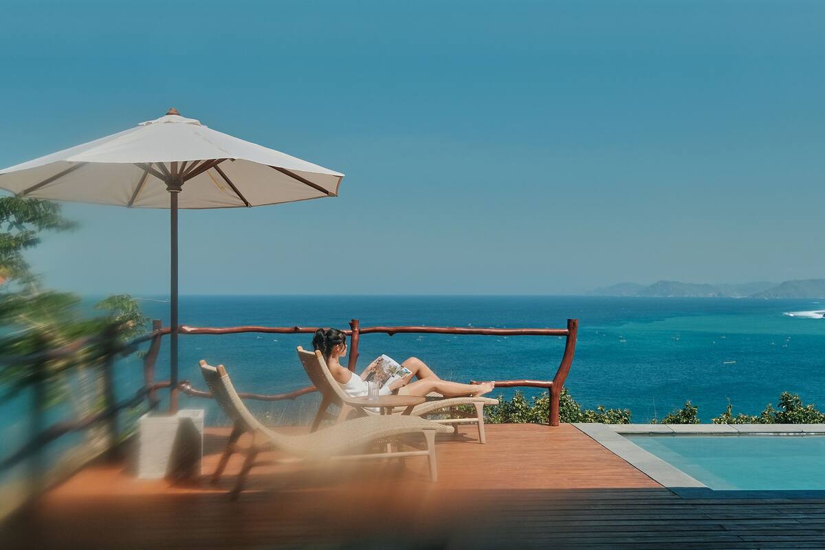 A person relaxing on a deck chair with a view of the ocean.
