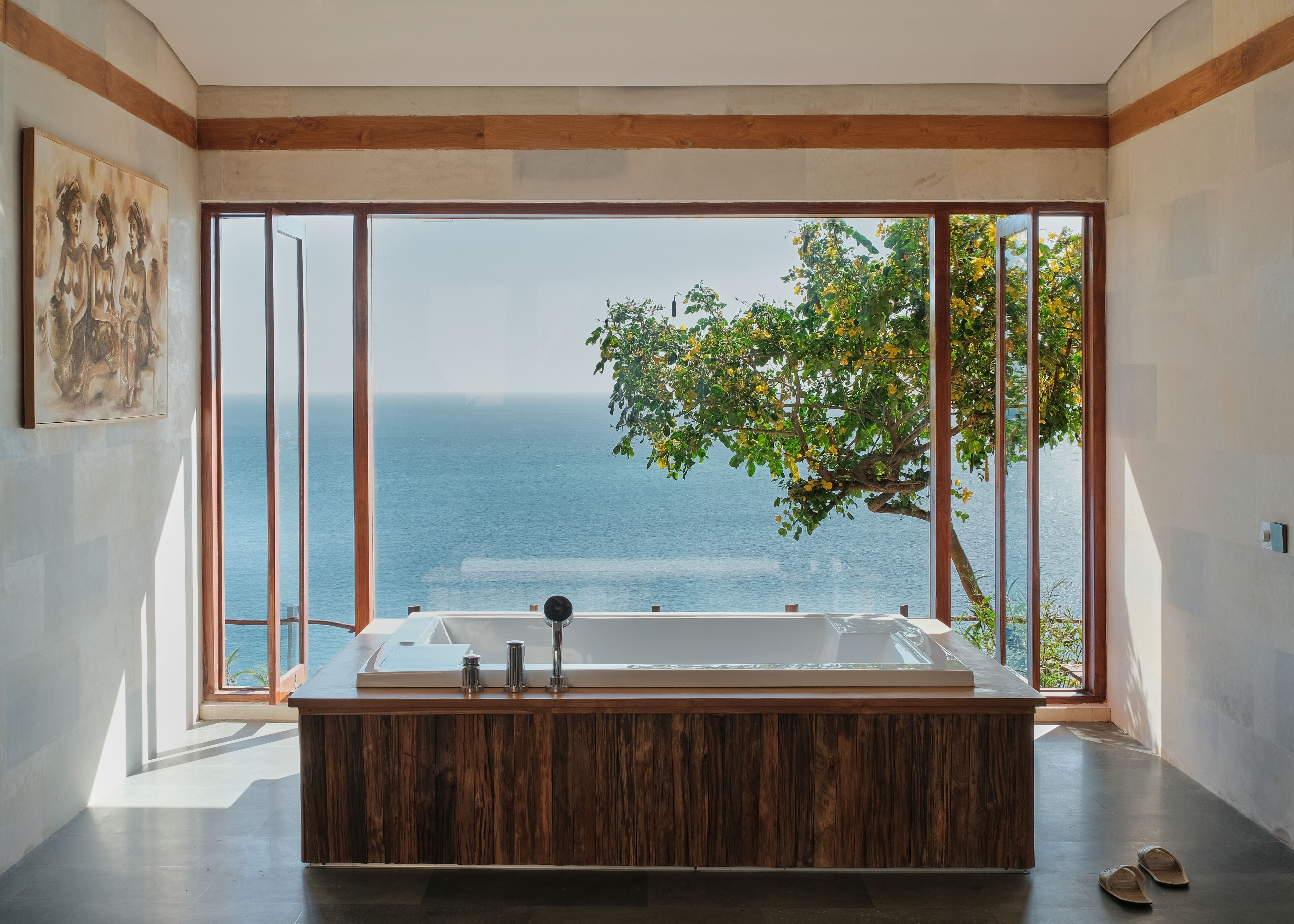 Ein modernes Badezimmer mit einer großzügigen Badewanne, Holzelementen und Meerblick.