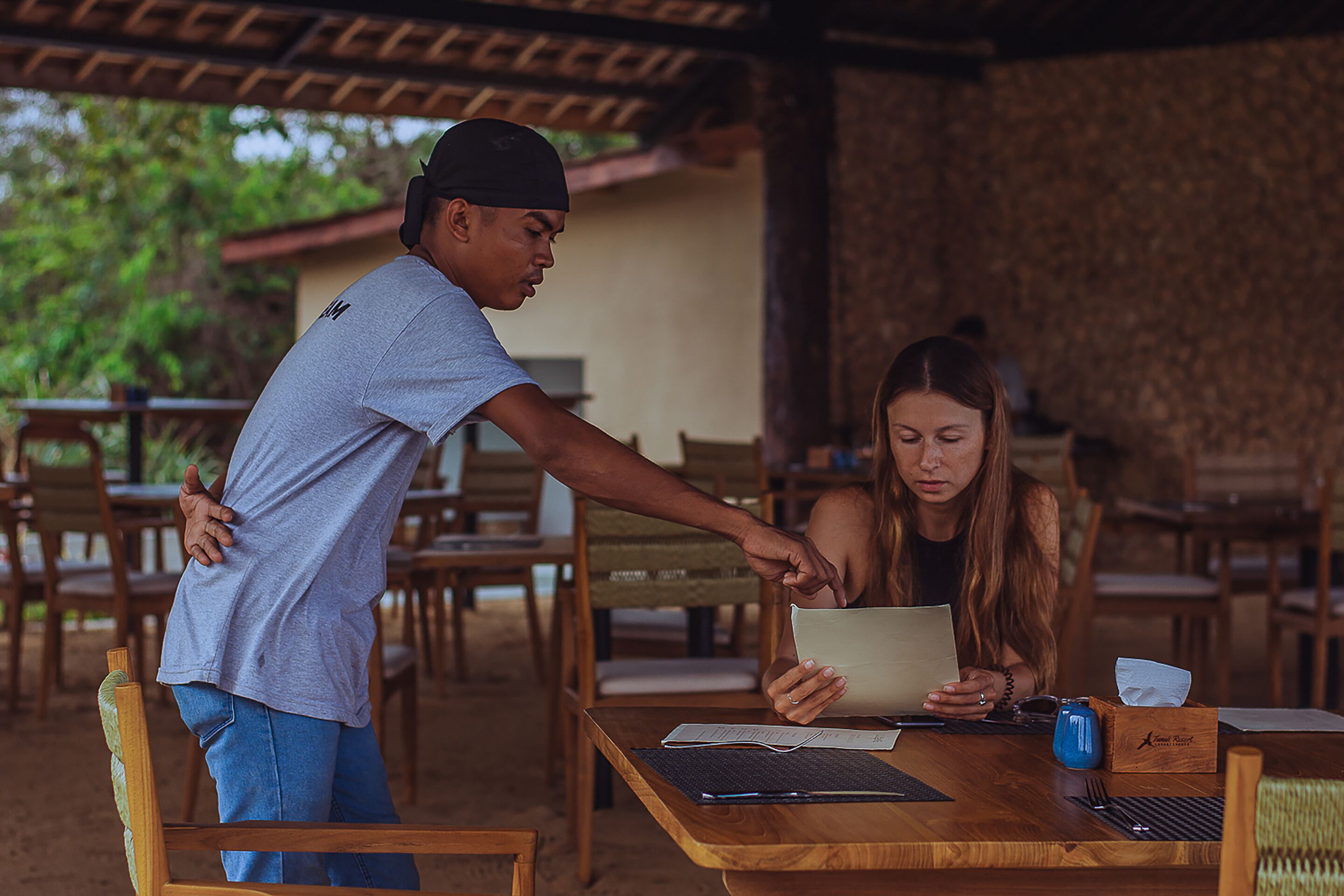 A wooden table with a laptop, papers, and a blue mug.