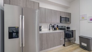 Una cocina moderna con armarios grises, electrodomésticos de acero inoxidable, un microondas integrado y un dispensador de agua.