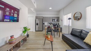 Apartamento moderno con sala de estar, comedor, cocina y un televisor grande mostrando servicios de streaming.