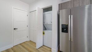 Una cocina moderna con un refrigerador de acero inoxidable, horno empotrado y un armario de madera.