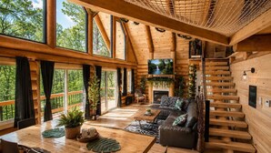 A spacious wooden cabin with a large dining table, a sofa, and a staircase.