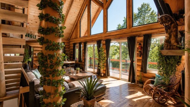 A log cabin interior with a dining area, a sofa, and a dog statue.