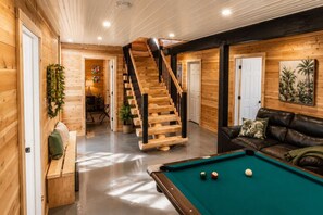 A wooden interior with a pool table, a leather sofa, and a staircase. - Welcome to the Jungle | Log cabine | Spa (Saint-Philémon)