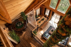 A wooden cabin with a green table, a sofa, and a staircase. - Welcome to the Jungle | Log cabine | Spa (Saint-Philémon)