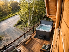 A wooden deck with a hot tub, outdoor seating, and a view of a forested area. - Welcome to the Jungle | Log cabine | Spa (Saint-Philémon)