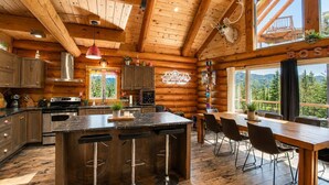 A log cabin interior with a kitchen, dining area, and large windows offering a view of the forest. - Private Heated Pool | Spa | Party | The Animal (Saint-Philémon)