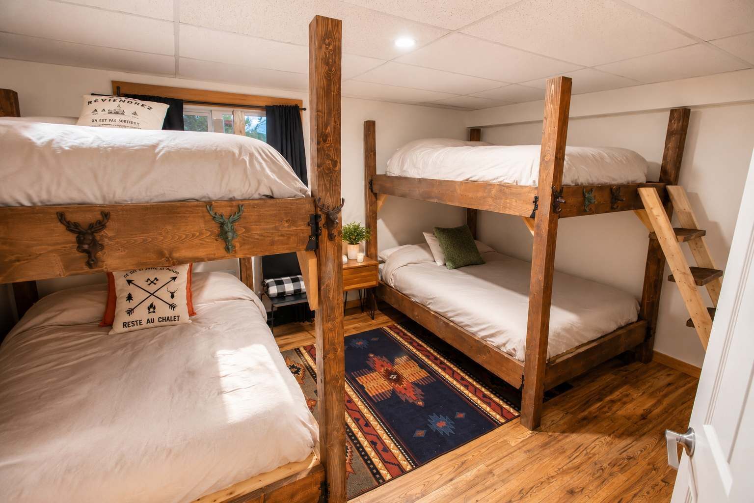 Una habitació amb tres llits superposats, un sòl de fusta, un tocador amb dibuixos i una finestra amb cortines.