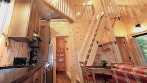 A wooden interior with a kitchen, dining area, and a loft bedroom.