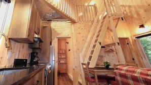 A wooden interior with a kitchen, dining area, and a loft bedroom.