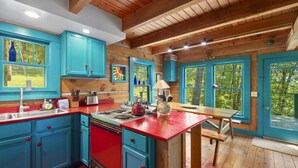 A kitchen with teal cabinets, a red stove, and wooden flooring. - Grandpa Dans Cabin+Mtn River view 34 acre retreat (Marshall)